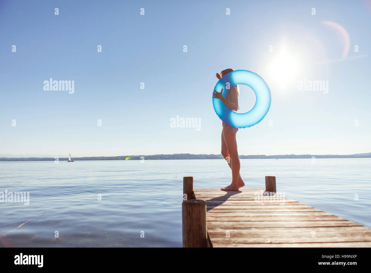 Giovane donna si erge sul molo dal lago di tenuta anello gonfiabile Foto Stock