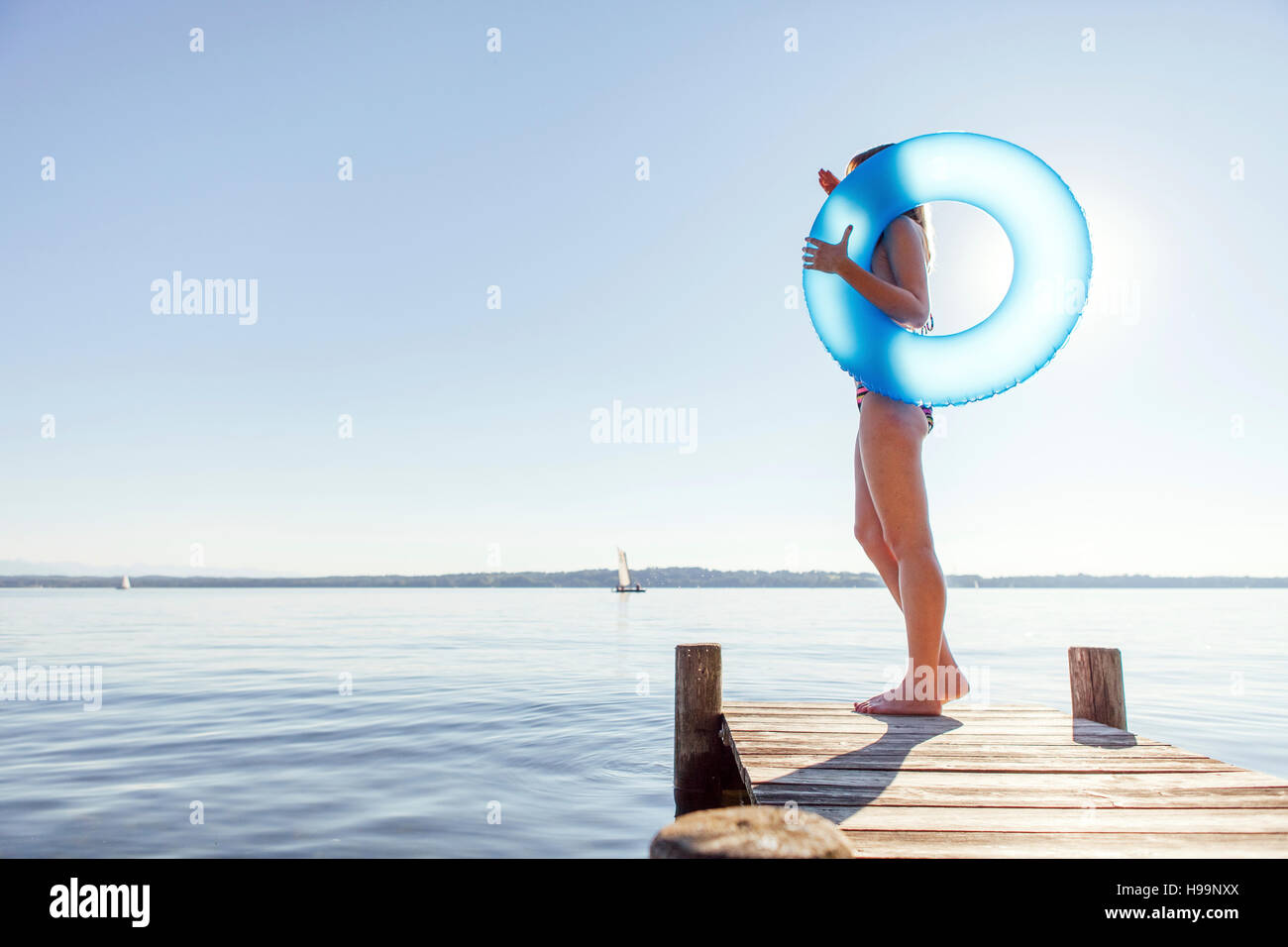 Giovane donna si erge sul molo dal lago di tenuta anello gonfiabile Foto Stock