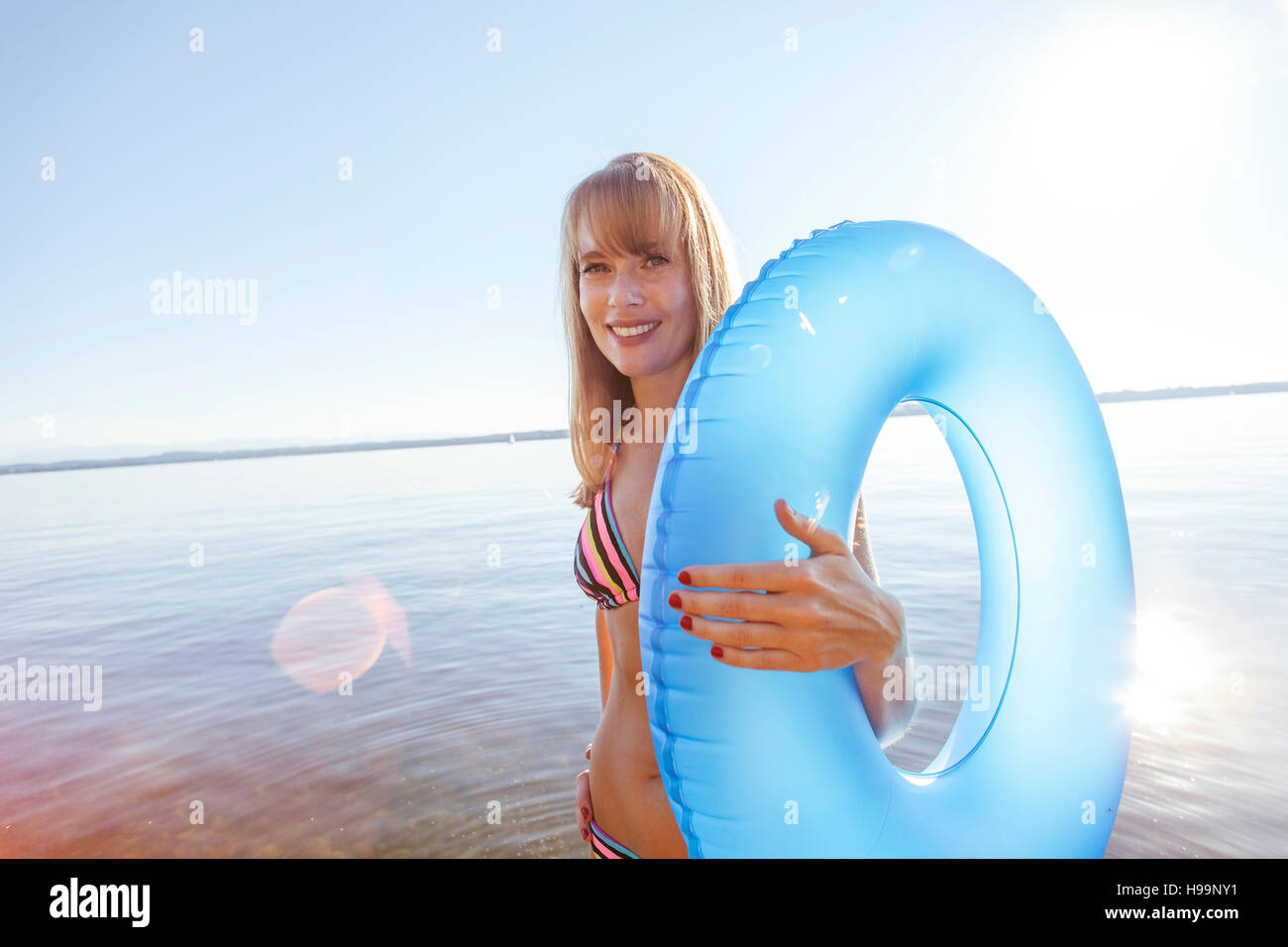 Giovane donna si erge sul molo dal lago di tenuta anello gonfiabile Foto Stock
