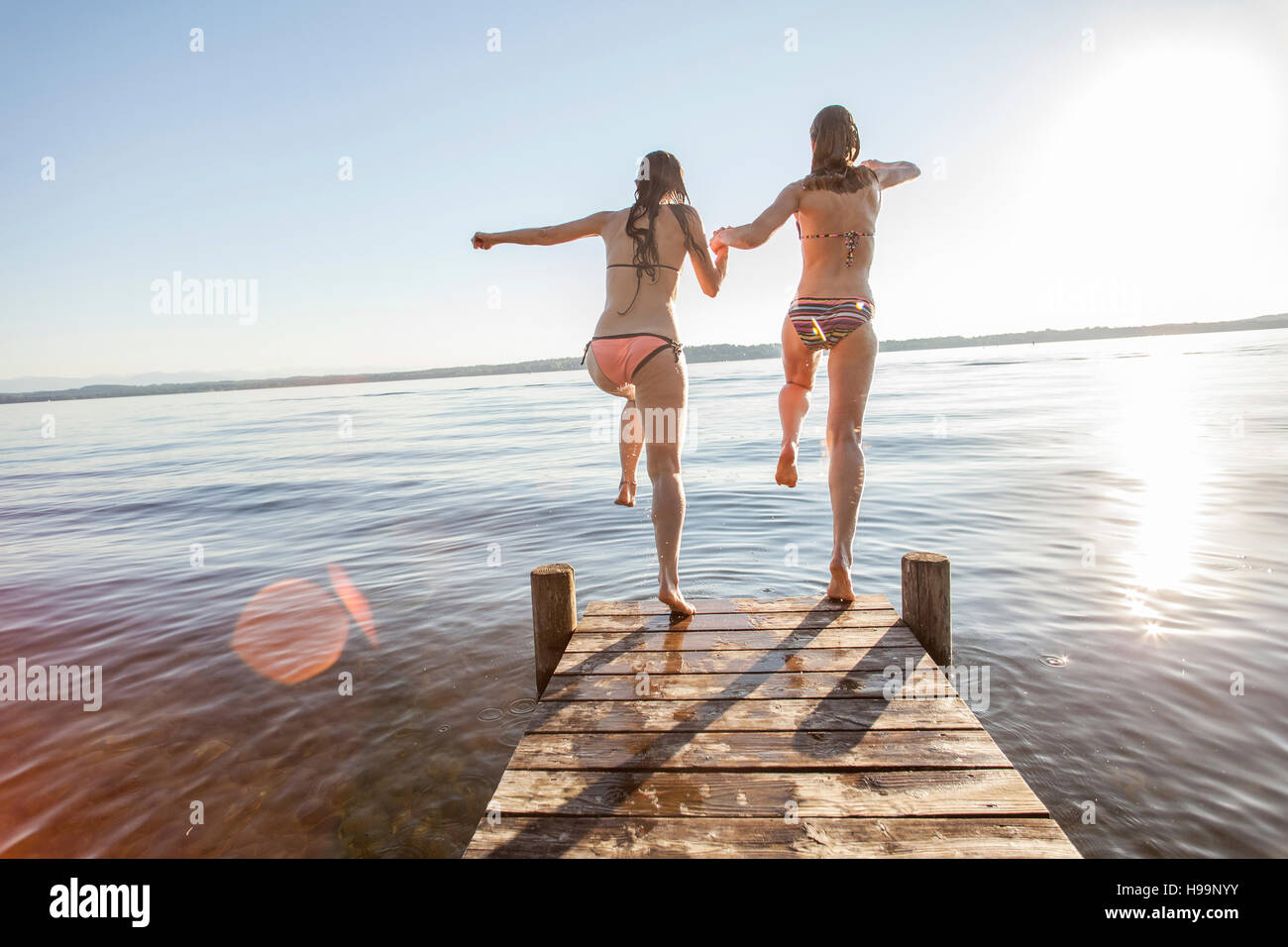 Due giovani donne saltando nel lago Foto Stock