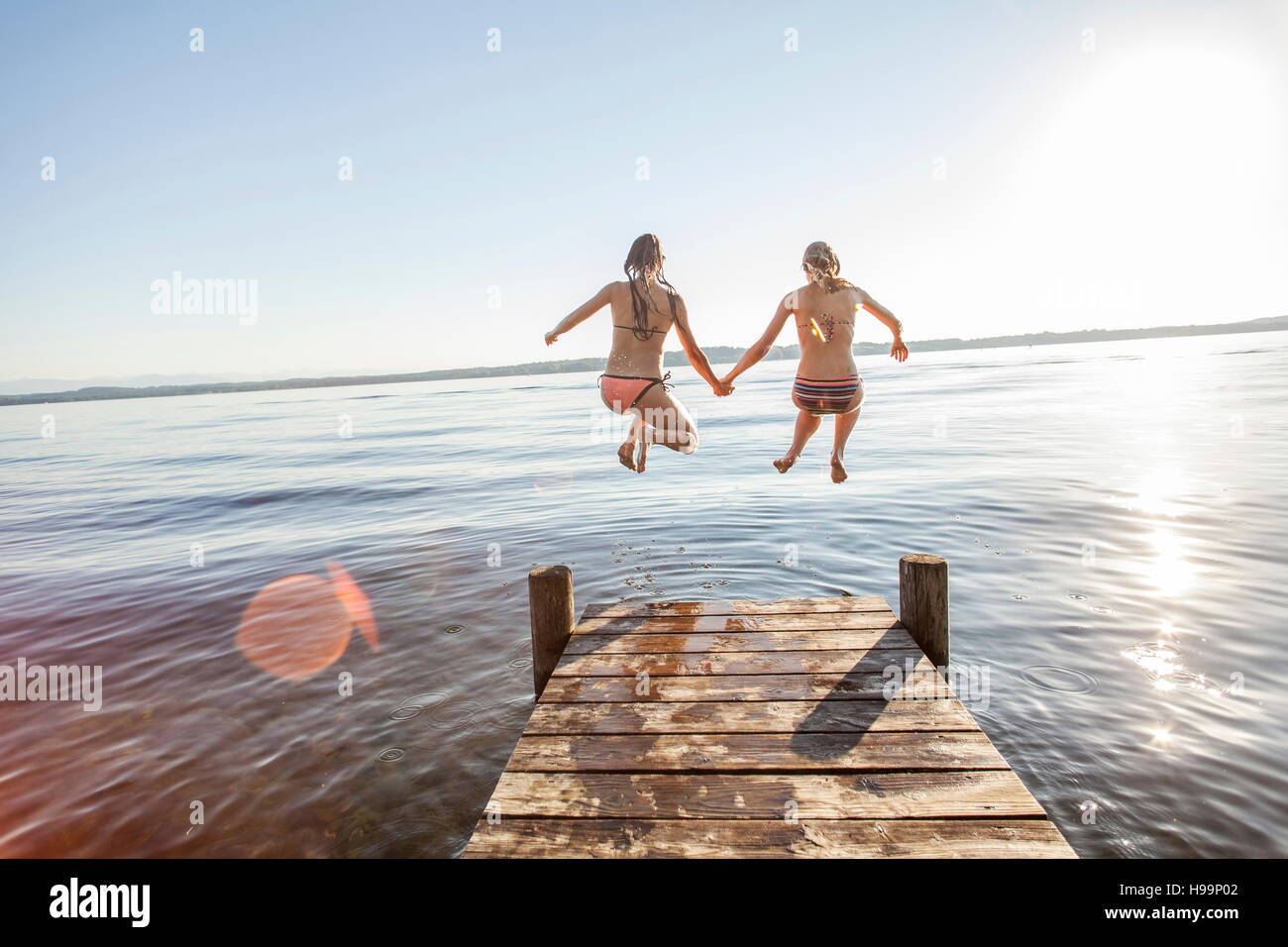 Due giovani donne saltando nel lago Foto Stock