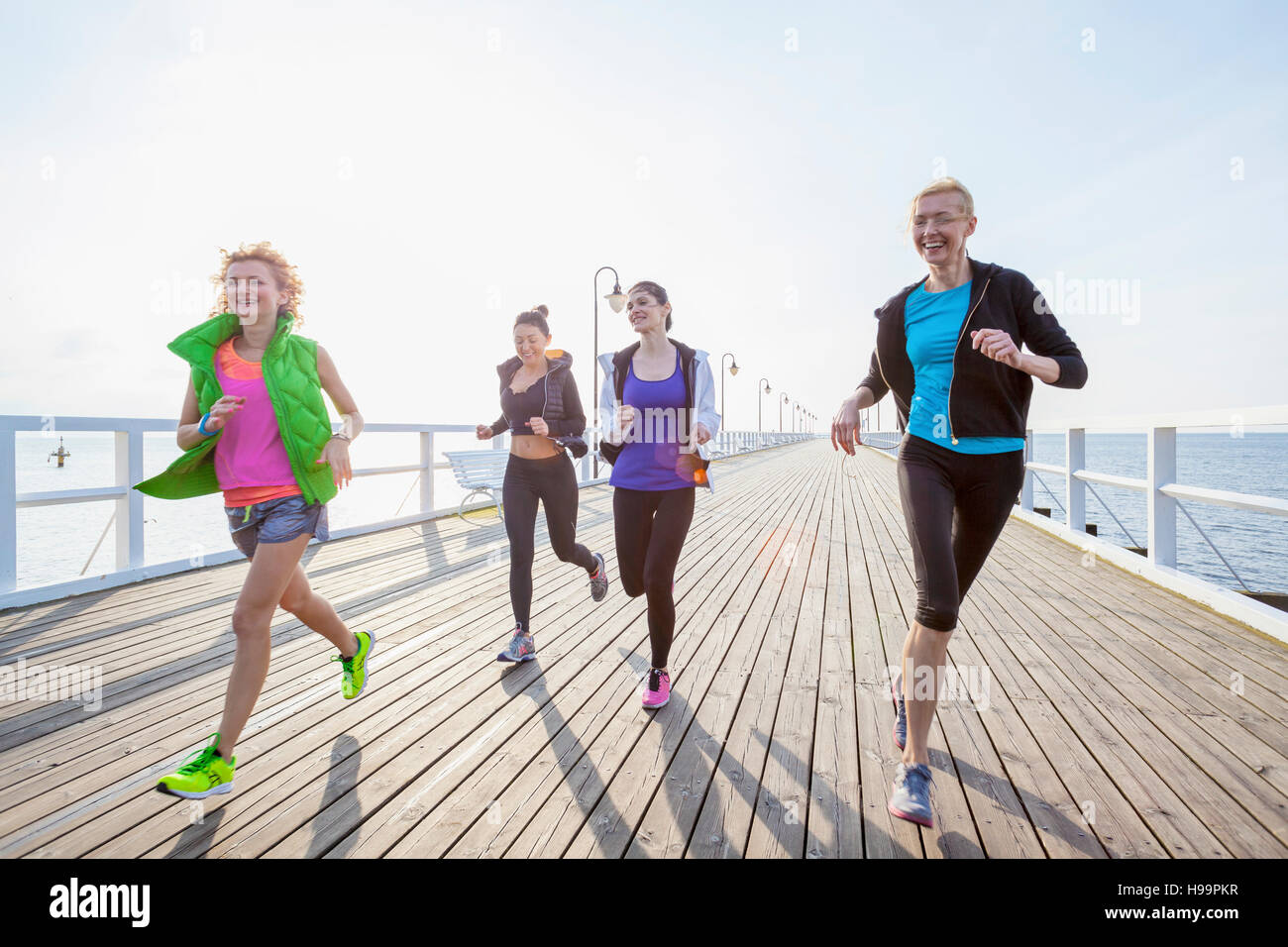 Il gruppo di donne in abbigliamento sportivo in esecuzione sul molo Foto Stock