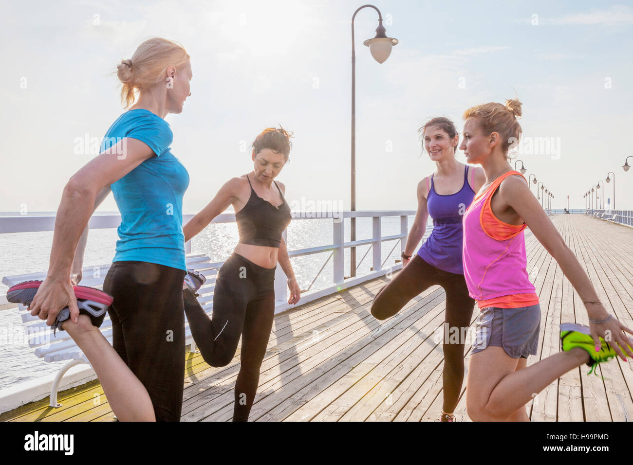 Il gruppo di donne stretching gambe su jetty Foto Stock