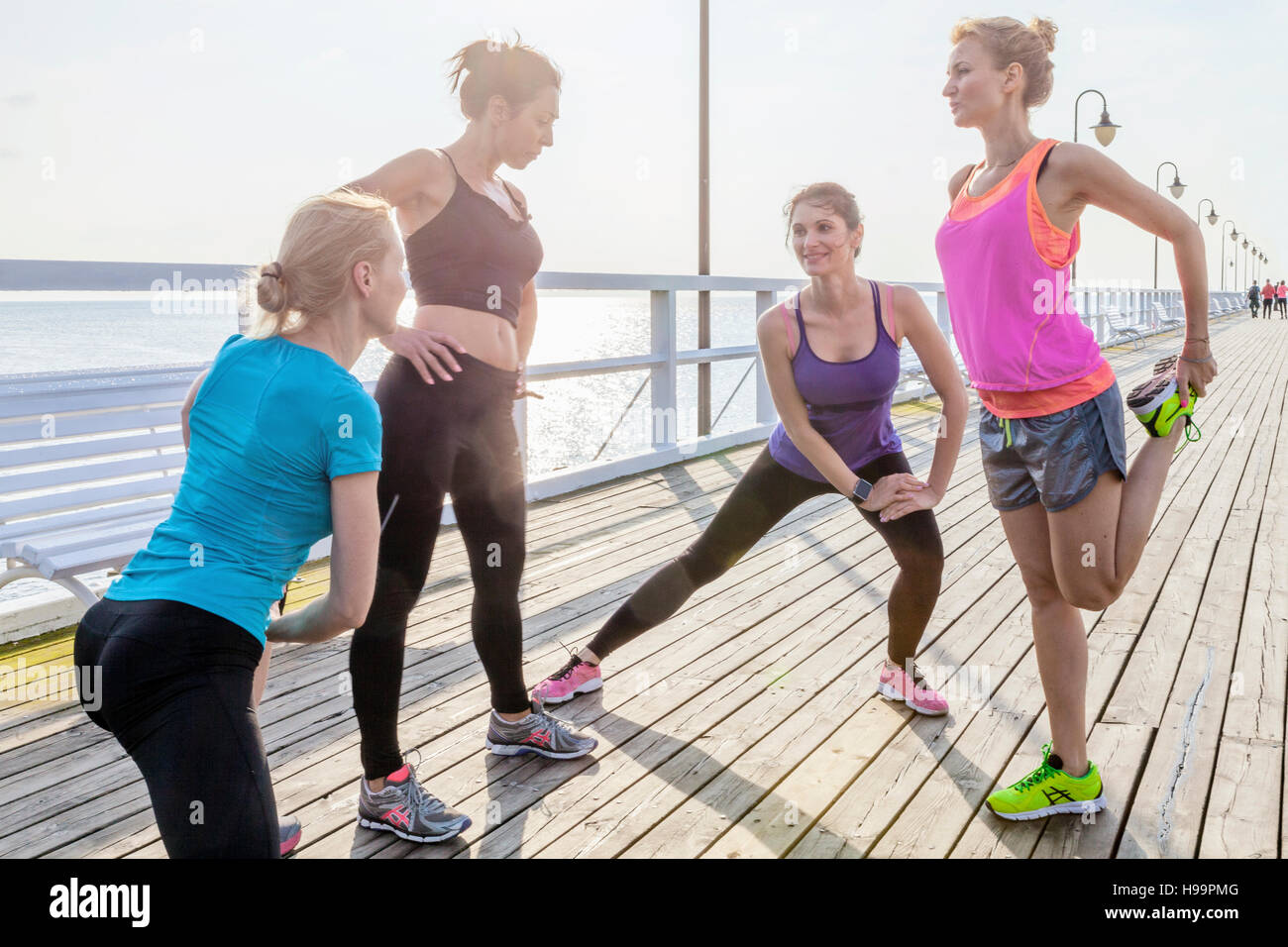 Il gruppo di donne stretching gambe su jetty Foto Stock