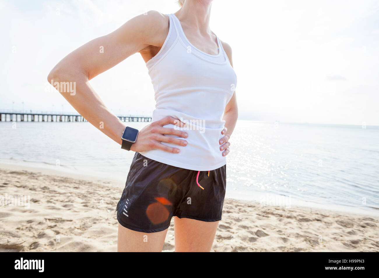 Donna in abbigliamento sportivo e il cronometro sulla spiaggia Foto Stock