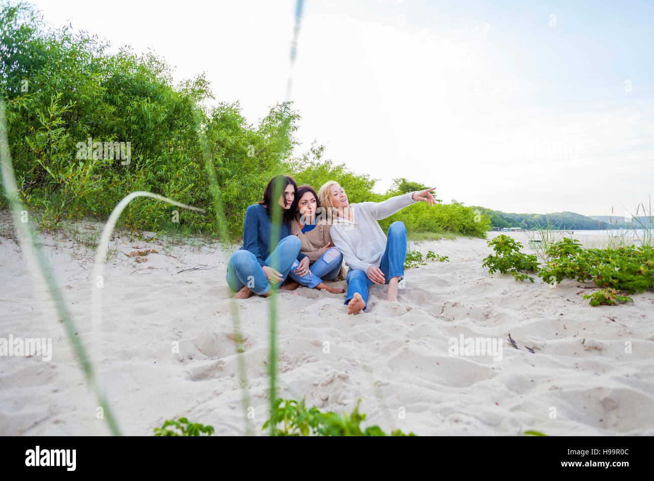 Il gruppo di donne seduto sulla spiaggia sabbiosa Foto Stock
