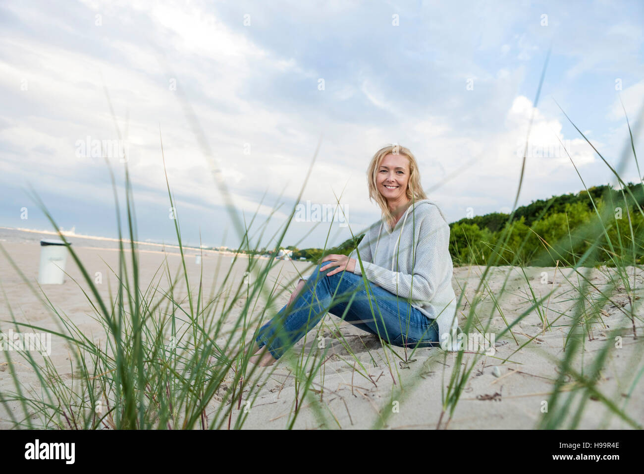 Donna con capelli biondi rilassante sulla spiaggia sabbiosa Foto Stock
