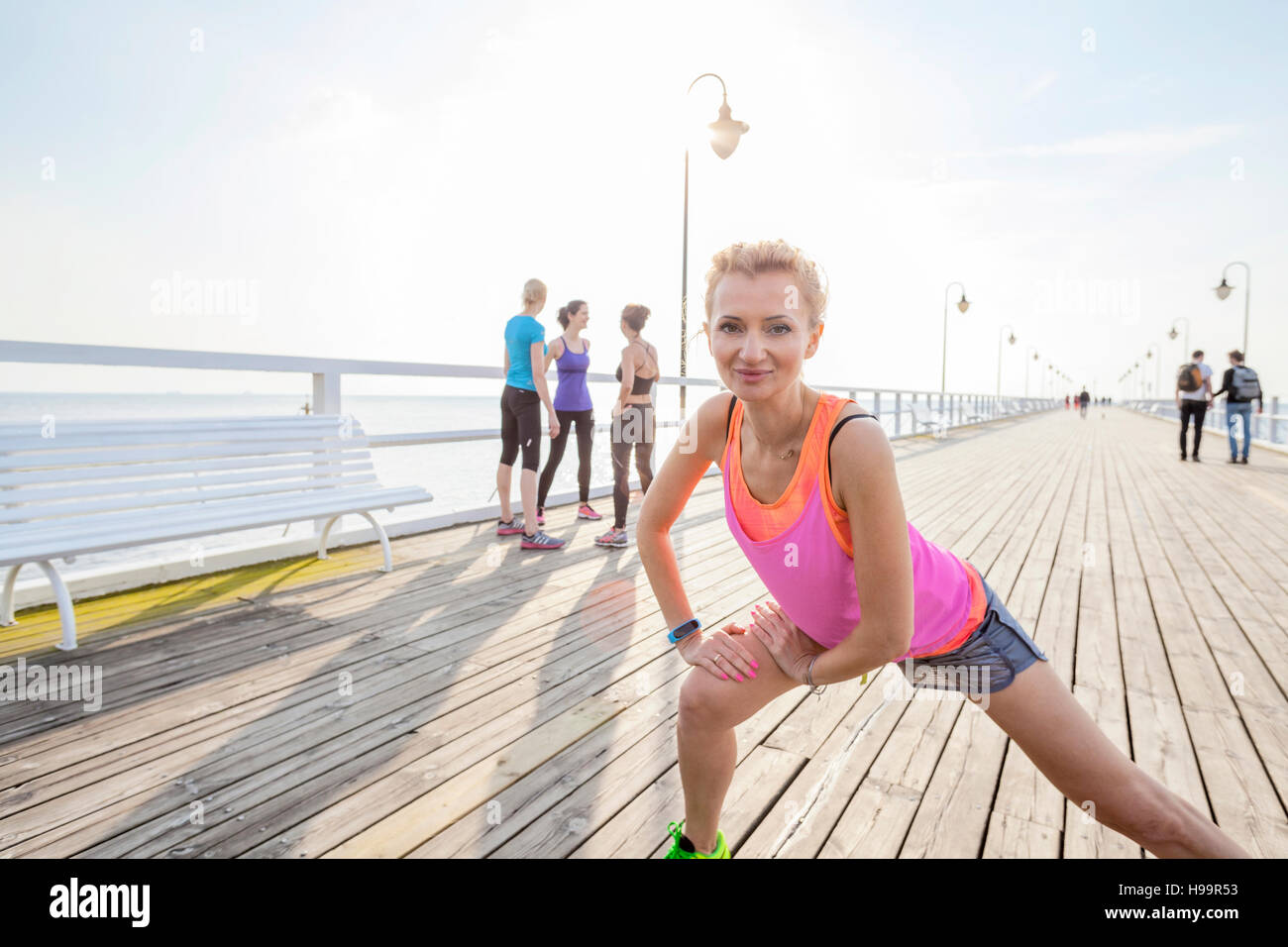 Donna sul molo facendo esercizio di stretching Foto Stock