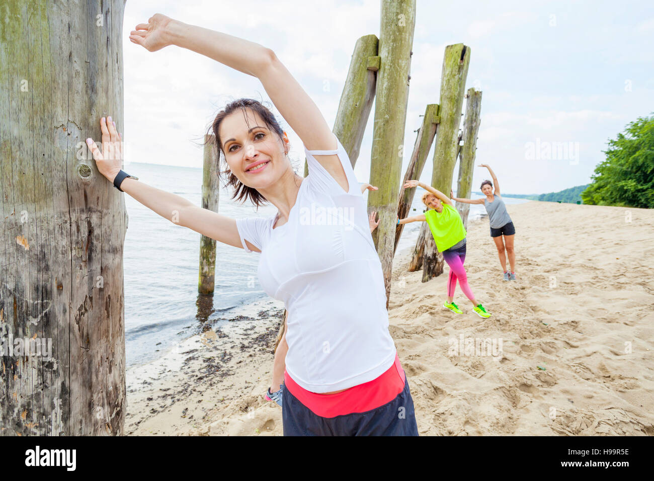 Le donne sulla spiaggia a fare esercizi di stretching Foto Stock