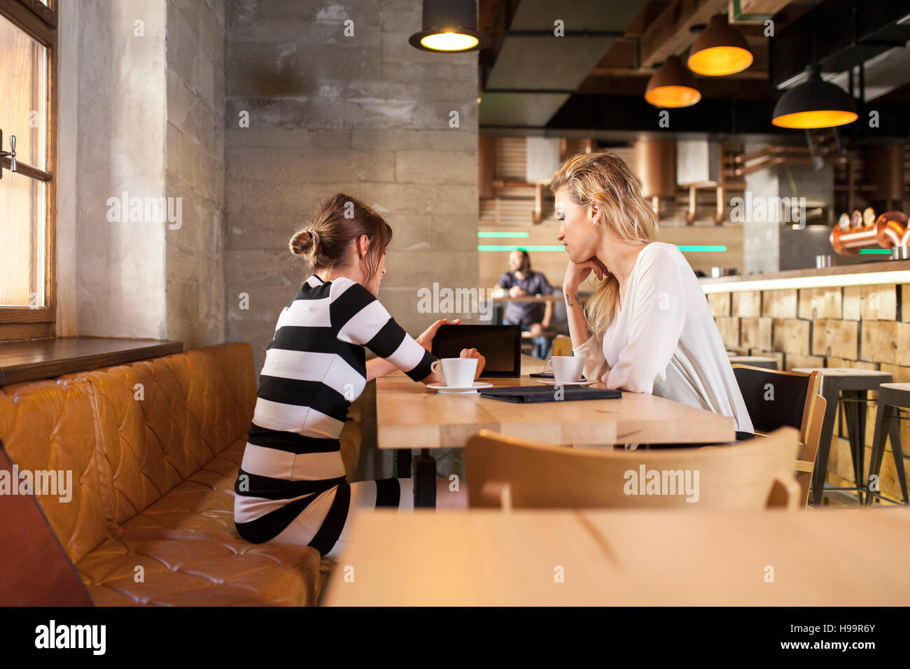 Due amiche nel negozio di caffè avente una conversazione Foto Stock