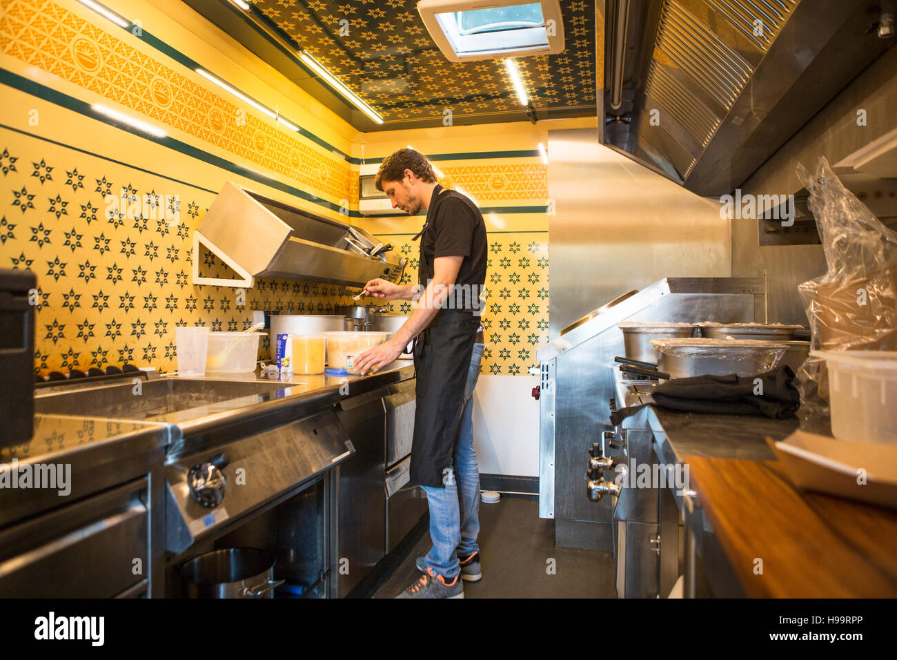 Imprenditore con grembiule lavora in cucina commerciale al cibo carrello Foto Stock