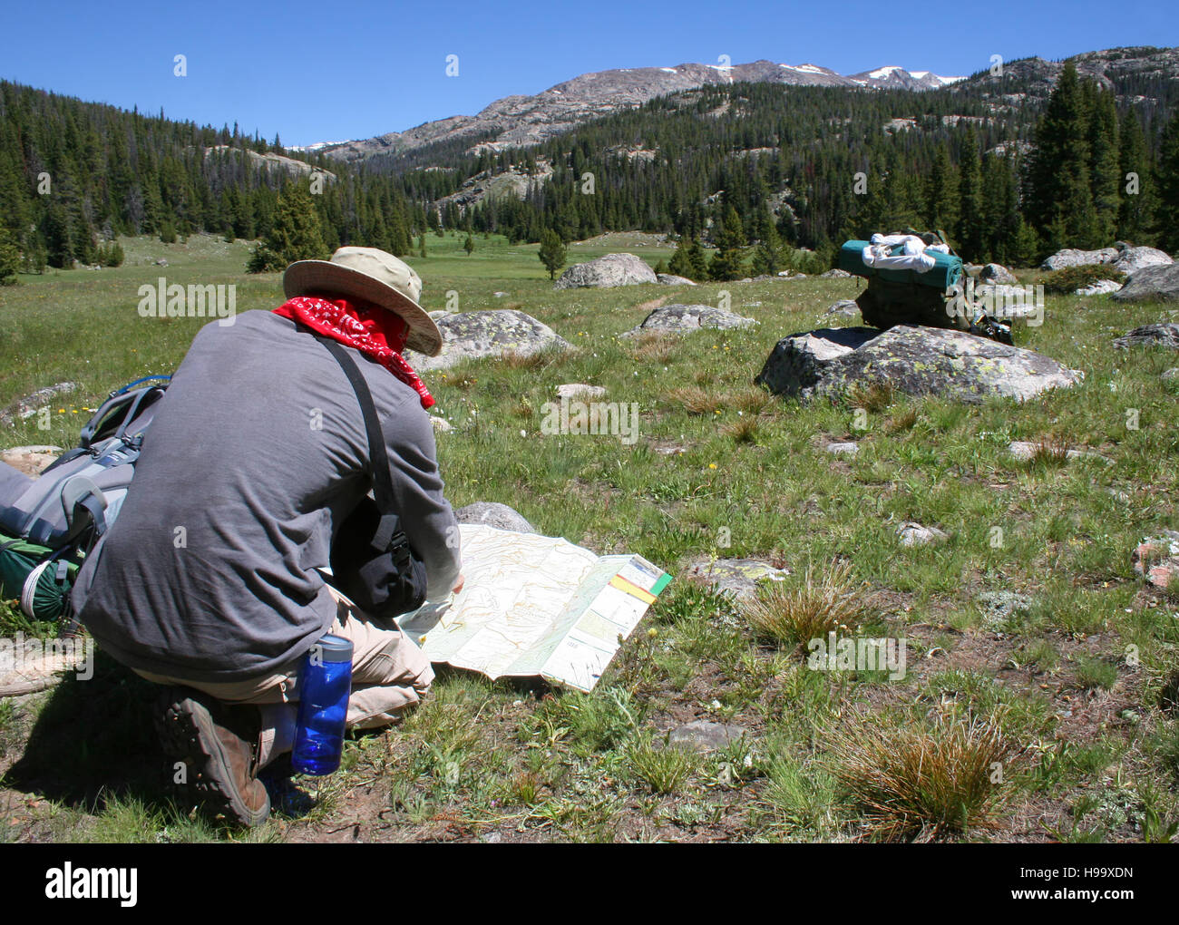 Un escursionista consulta la mappa per navigare versanti scoscesi. Foto Stock