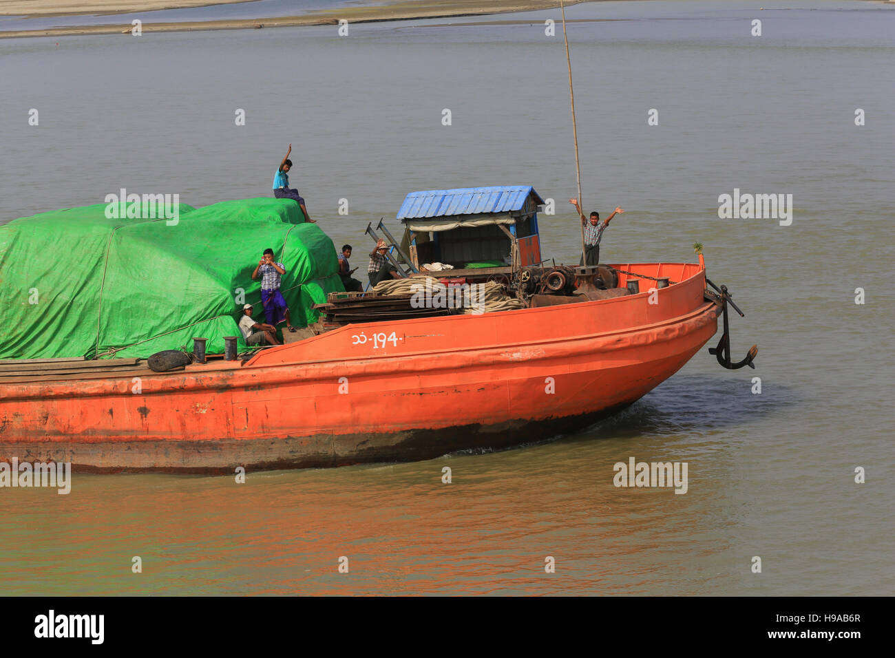 Equipaggio su un fiume bettolina, andando a monte, wave a turisti su una nave da crociera sul fiume Irrawaddy in Myanmar (Birmania). Foto Stock