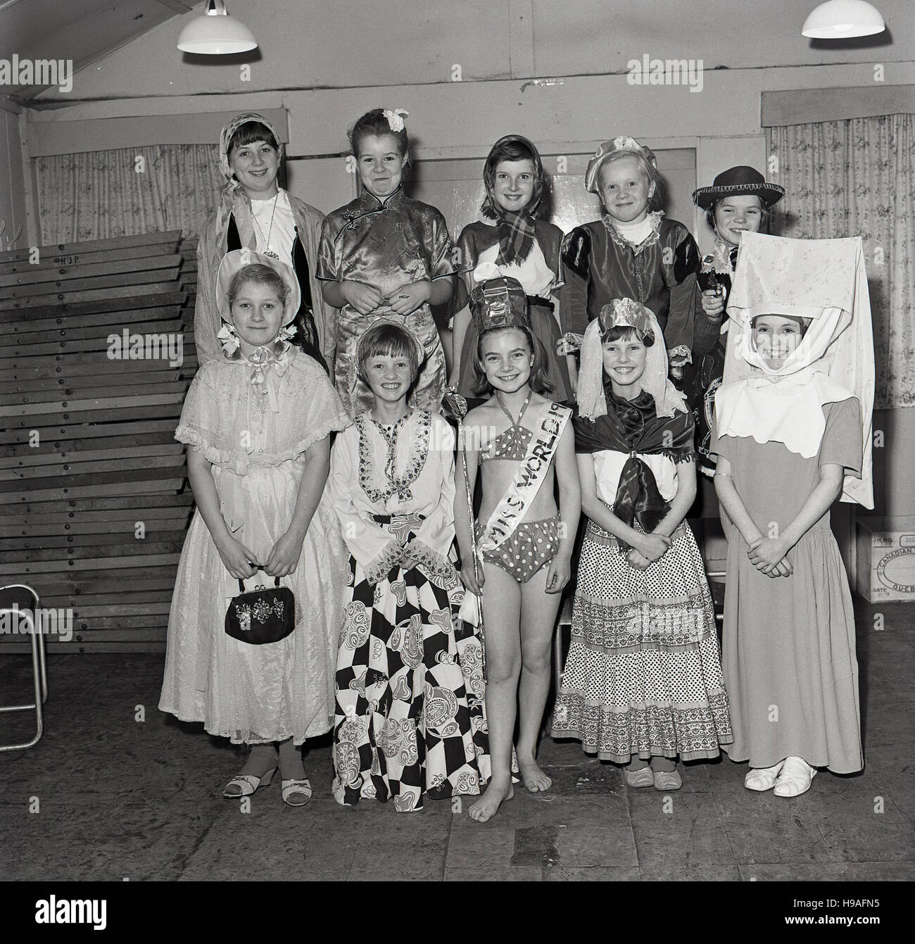 1965, storico, sorridenti ragazze che posano per una foto di gruppo nei loro abiti fantasiosi costumi Foto Stock