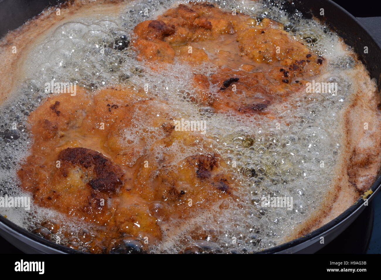 Friggere Wiener Schnitzel in una ghisa pan Foto Stock