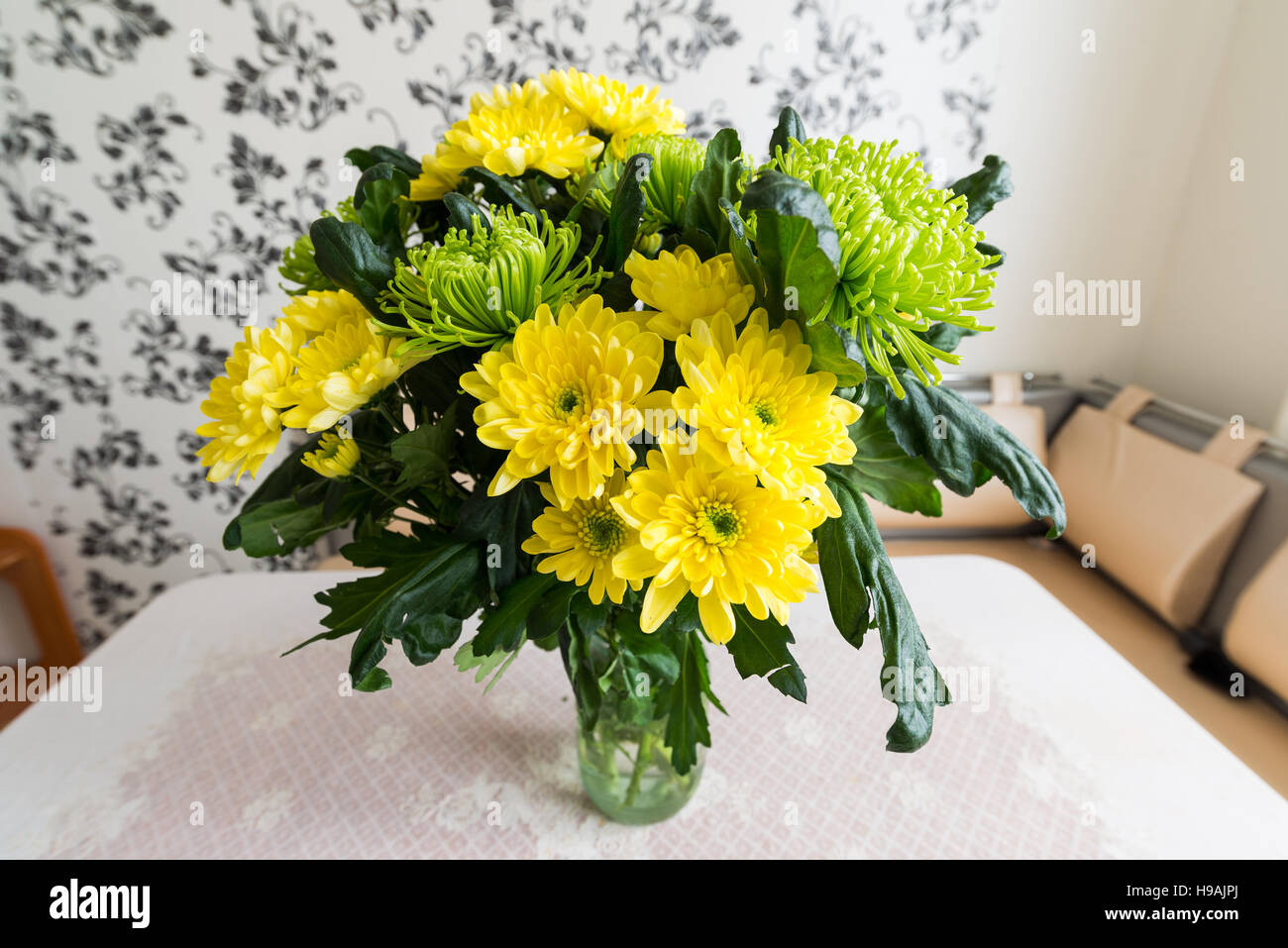 Bouquet di giallo e verde crisantemi in piedi sul tavolo della cucina Foto Stock