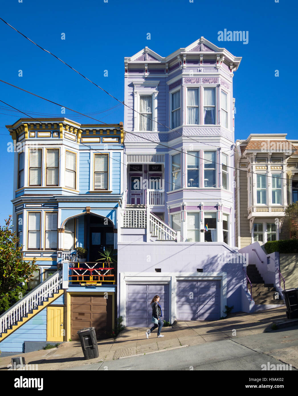 Una ragazza cammina su Sanchez Street (nota architettura Victorian-Italianate) nel quartiere Castro di San Francisco, California. Foto Stock