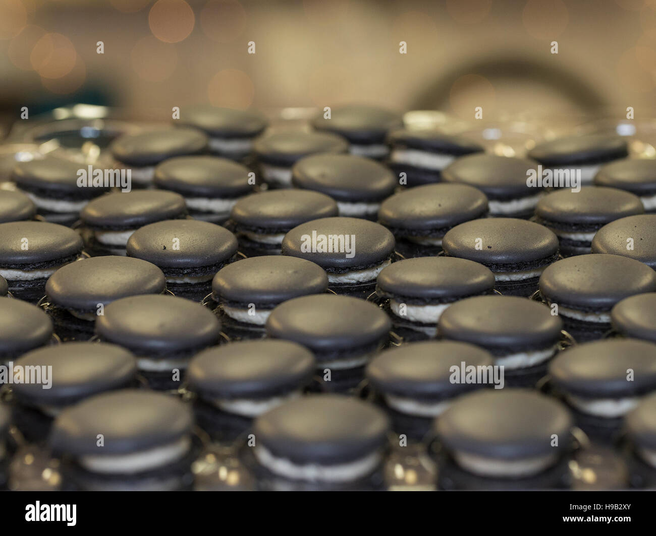 Le righe dei fatti a mano di meringa nero french macarons con crema bianca a artigianale mercato alimentare Foto Stock