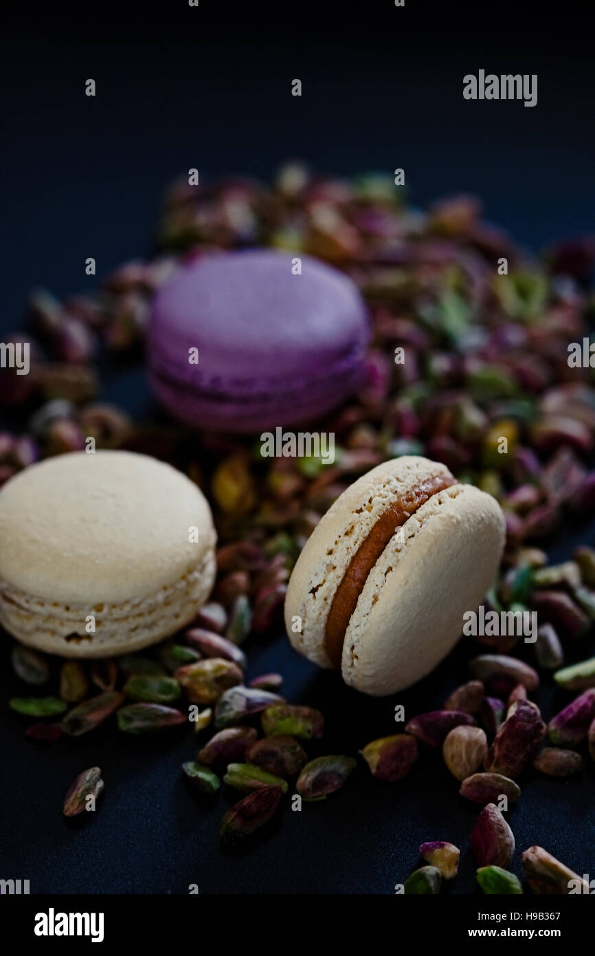 Giallo pallido e viola gli amaretti con trito di pistacchi di Bronte. Bella scuro fotografia di cibo Foto Stock