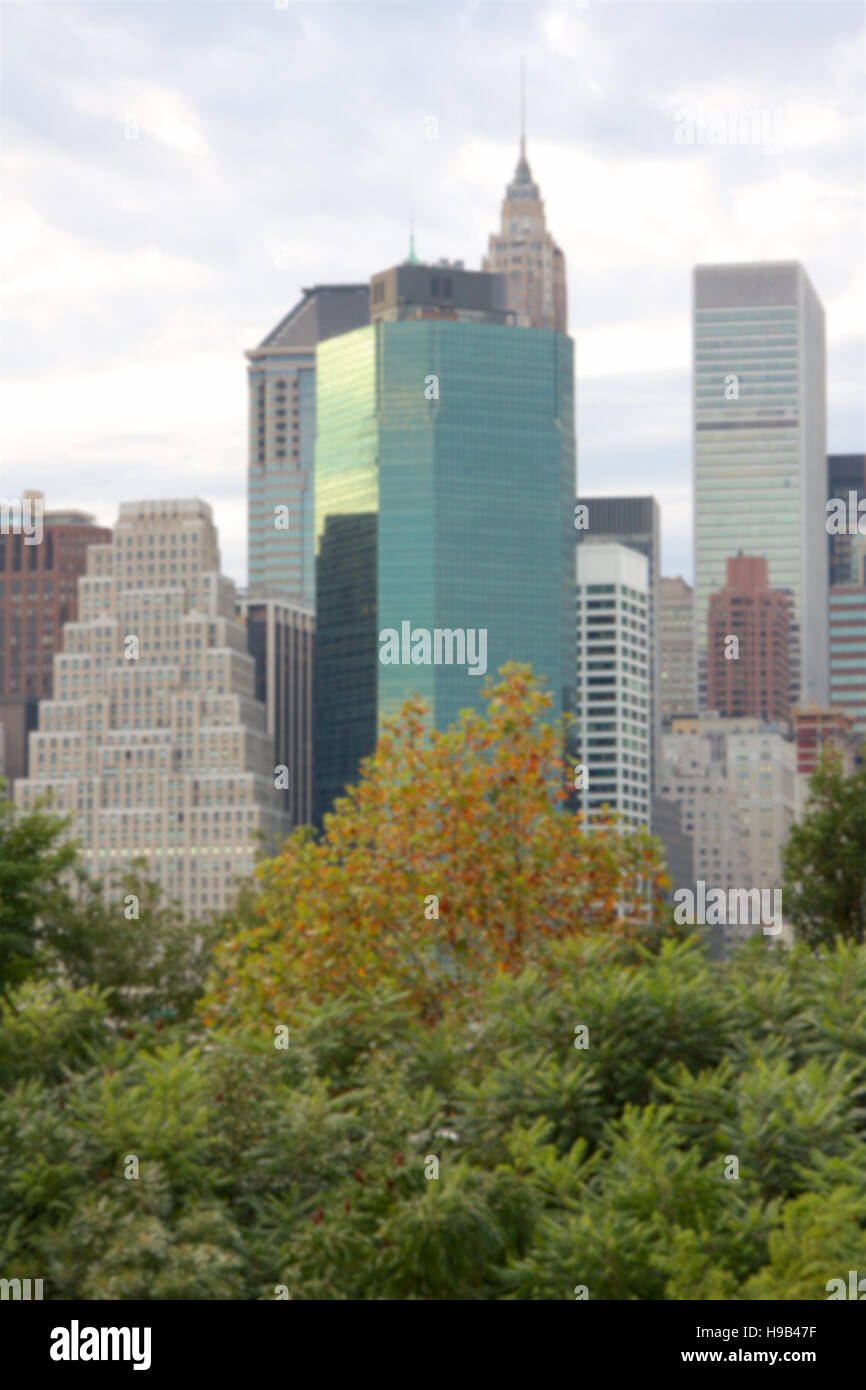 Sfocatura dello sfondo dello skyline di Manhattan visto da dietro e sopra gli alberi a Ponte di Brooklyn Park di New York, NY, STATI UNITI D'AMERICA. Foto Stock