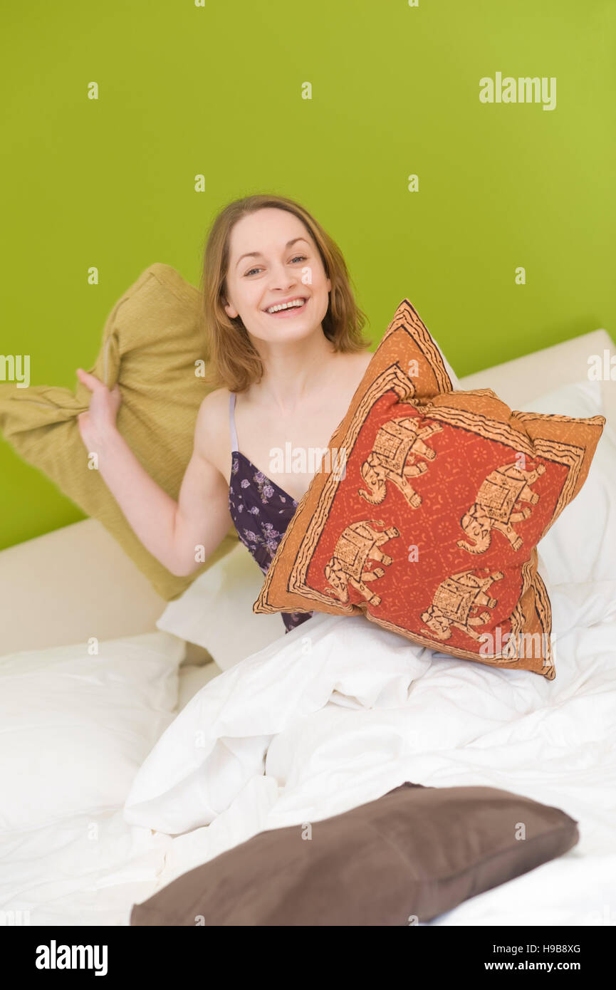 Giovane donna a letto con cuscini Foto Stock