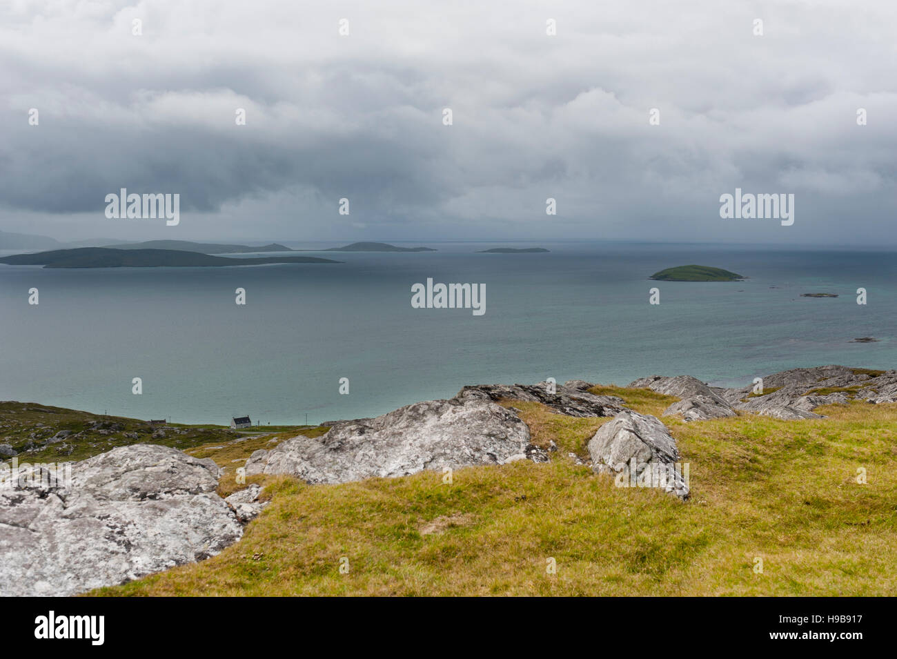 Erba e rocce, mare e isole, vista dalla montagna Beinn Sciathan dell Atlantico, Isola di Eriskay, Ebridi Esterne, Scozia Foto Stock