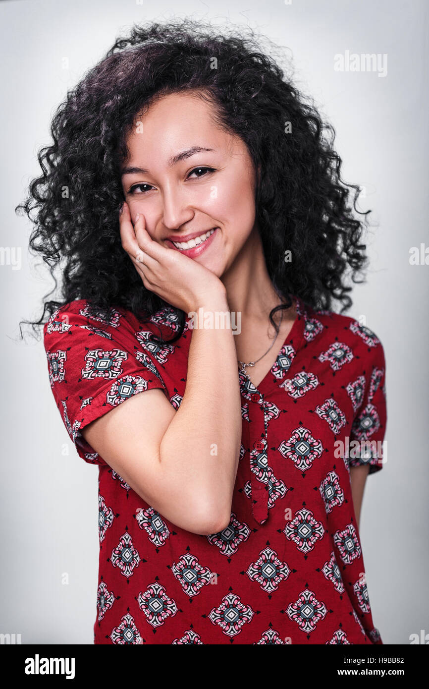 Giovane donna sorridente con ricci capelli neri Foto Stock
