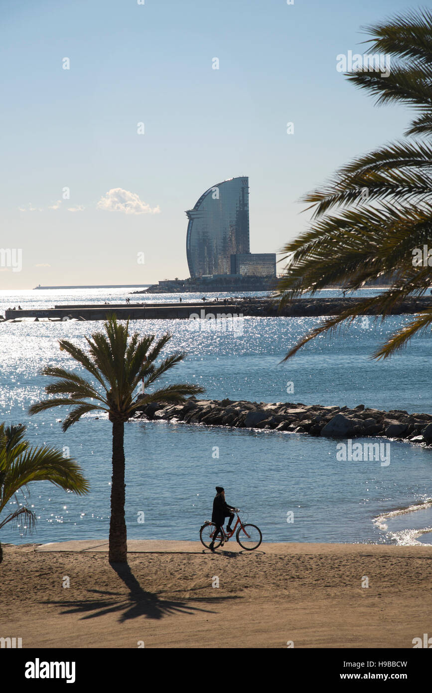 Vista del World Trade Center di Barcellona, con una ragazza su una bicicletta, palme e Spiaggia di primo piano Foto Stock