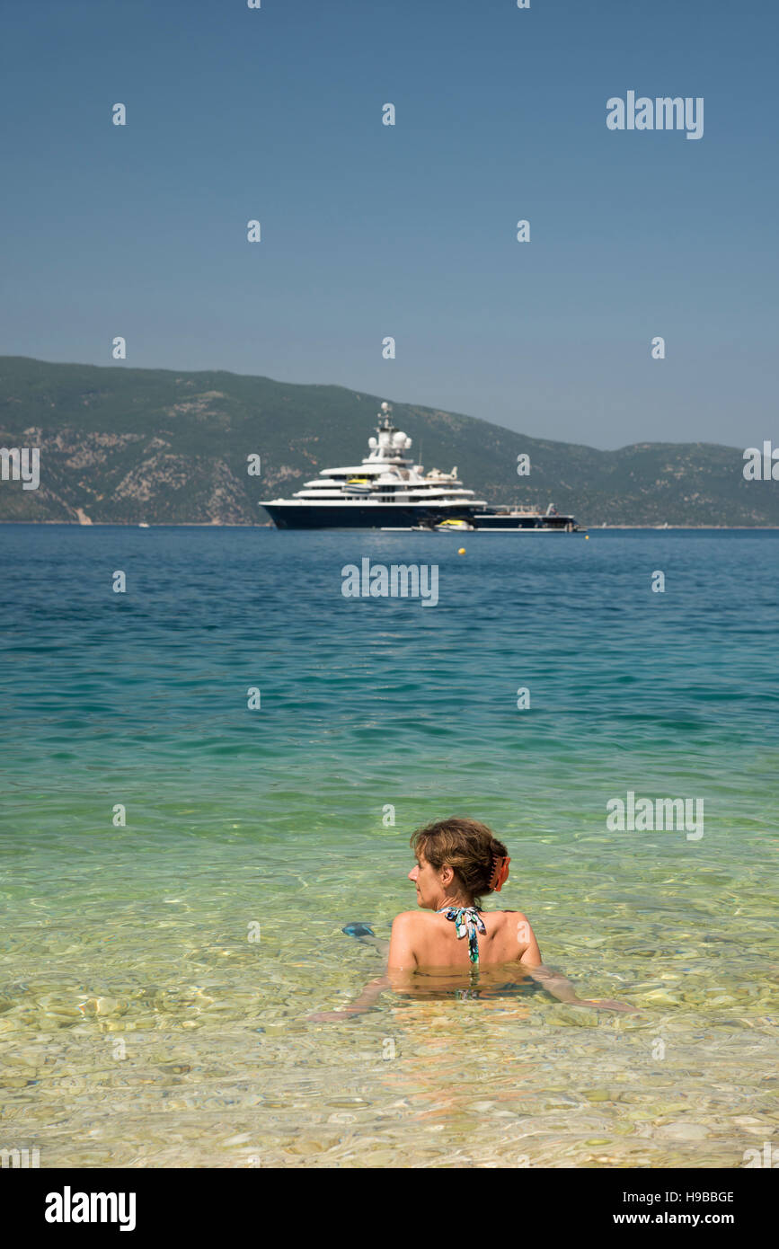 Bella Donna seduta rilassante nel Mar Ionio a Cefalonia, guardando il lussuoso yacht Luna, precedentemente di proprietà di Roman Abramovich Foto Stock