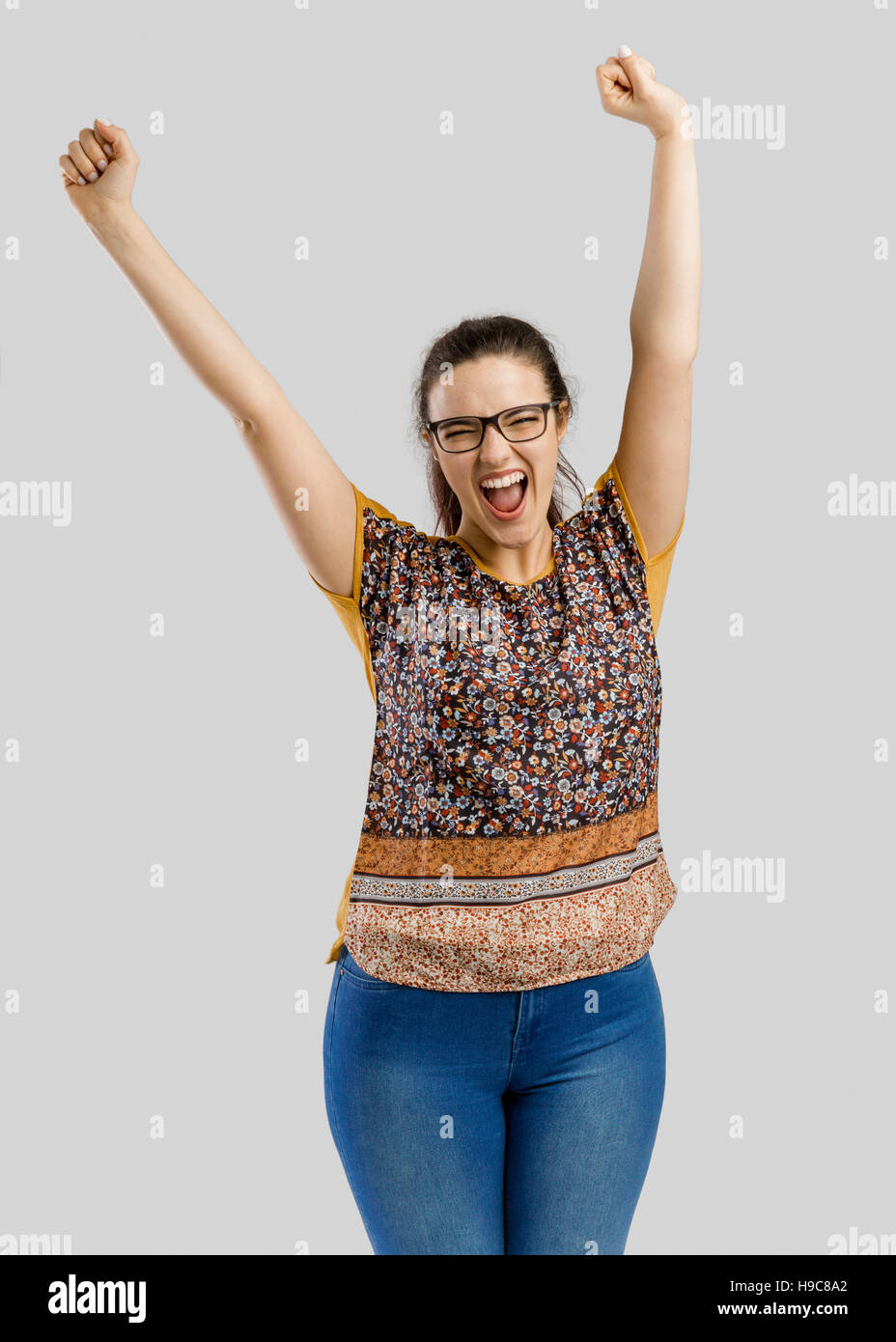Bella e felice donna con entrambe le braccia in alto, isolate su uno sfondo grigio Foto Stock