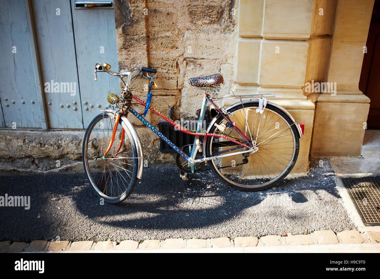 Un multi-colore di bicicletta con un vecchio bell nel centro storico della città di Pézenas, Francia Foto Stock