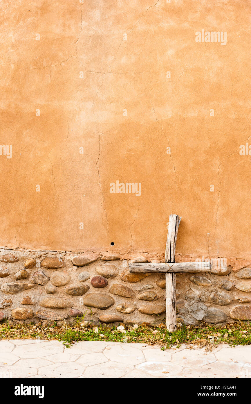 Croce rustica in legno fatta a mano, crocifisso poggiato contro una parete della chiesa nel Santuario de Chimayó, New Mexico, USA Foto Stock