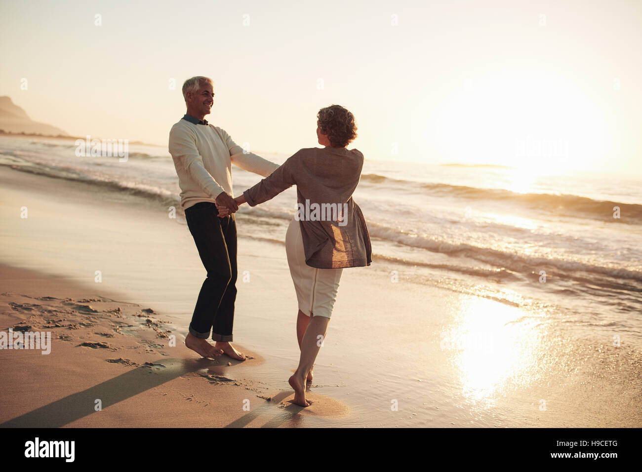 Romantico Coppia matura godendo una giornata in spiaggia. Coppia matura in piedi insieme tenendo le mani. Foto Stock