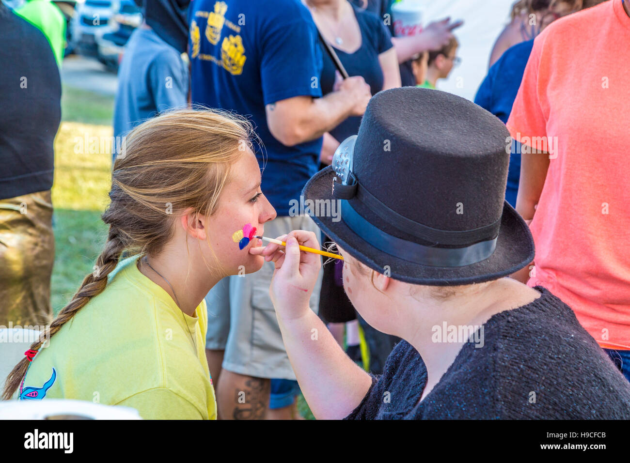 Giovane donna ottenendo il suo volto dipinto a una caduta festival di Gulfport, Mississippi Foto Stock