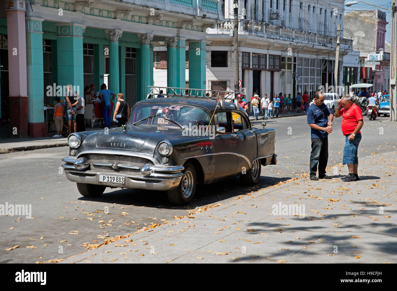 Due uomini cubani parlare in piedi accanto a un travagliato vecchio ci classic vintage in auto le strade di Cienfuegos Cuba Foto Stock