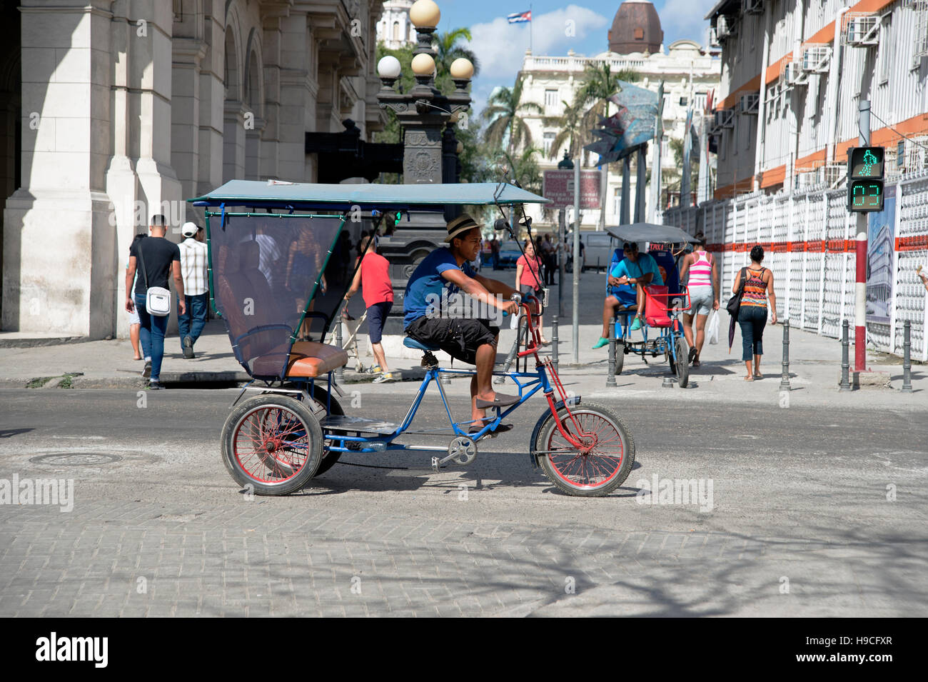 Un uomo cubano guida il suo taxi in bicicletta a tre ruote in risciò sulle strade trafficate di l'Avana Vieja Cuba Foto Stock
