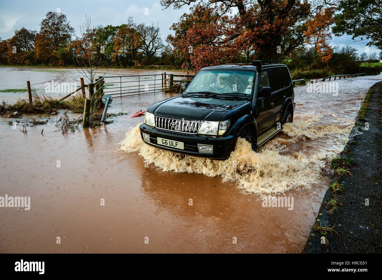 Un 4x4 ventures attraverso le profonde acqua di inondazione sulla strada della stazione, Broadclyst, Devon, dove i fiumi hanno hanno rotto gli argini e chiuso le strade principali a sud del villaggio. Foto Stock
