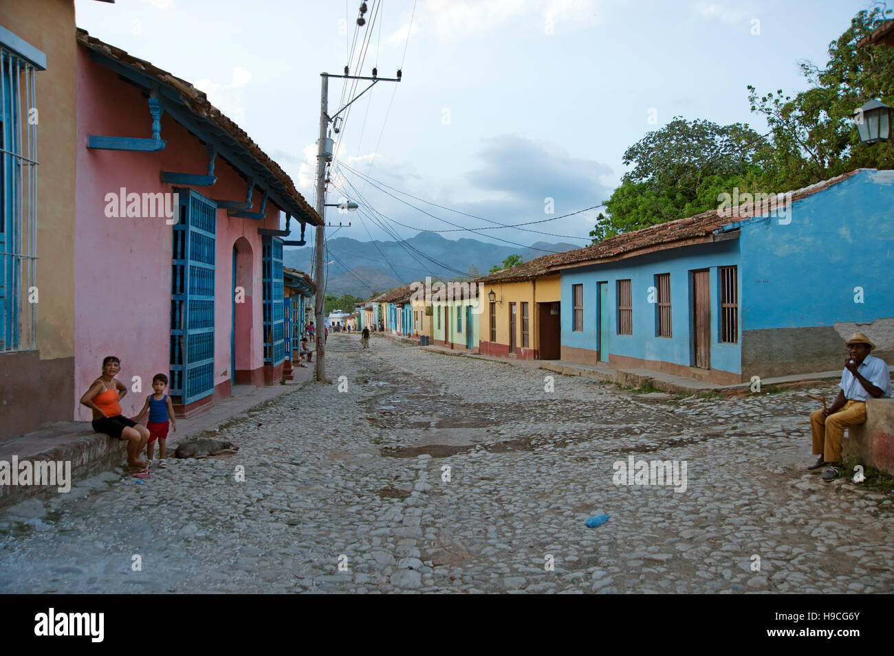 Guardando giù per una strada in Trinidad Cuba con pastello colouful case dipinte su entrambi i lati e gente seduta fuori Foto Stock