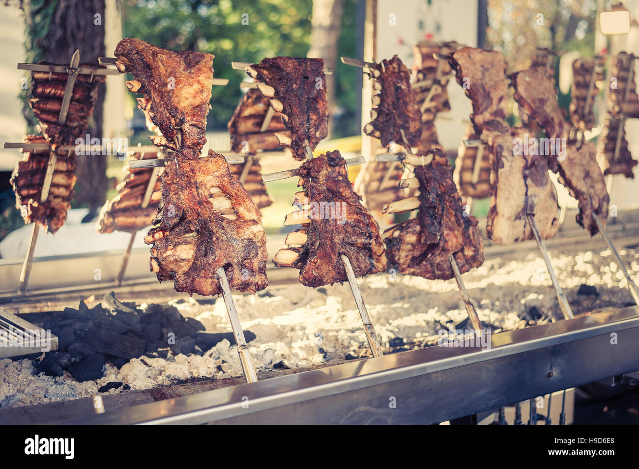 Asado, barbecue tradizionale piatto in Argentina, carne arrosto di manzo cotta su griglie verticali collocati intorno al fuoco. Look vintage Foto Stock
