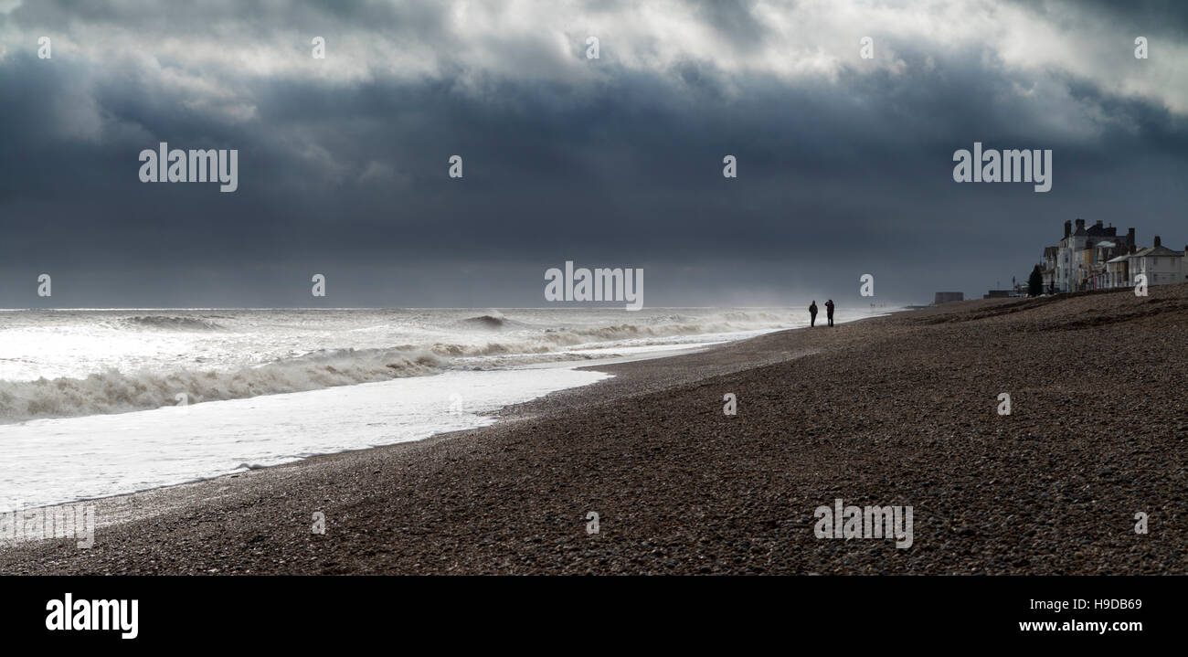La spiaggia di Aldeburgh Suffolk in Inghilterra in mattina presto luce durante una tempesta con mare mosso con il profilarsi la gente sulla riva Foto Stock