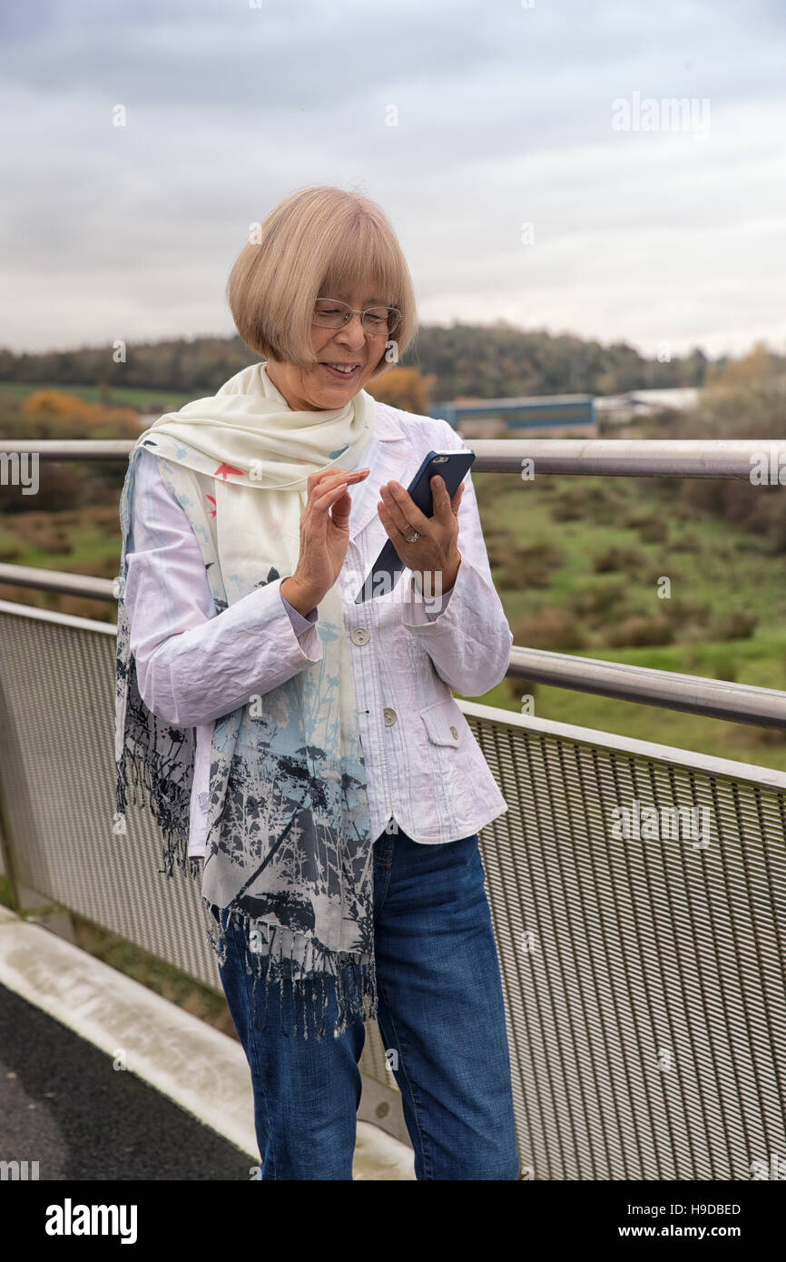 Anziani donna giapponese utilizzando uno smart phone per inviare un messaggio di testo Foto Stock
