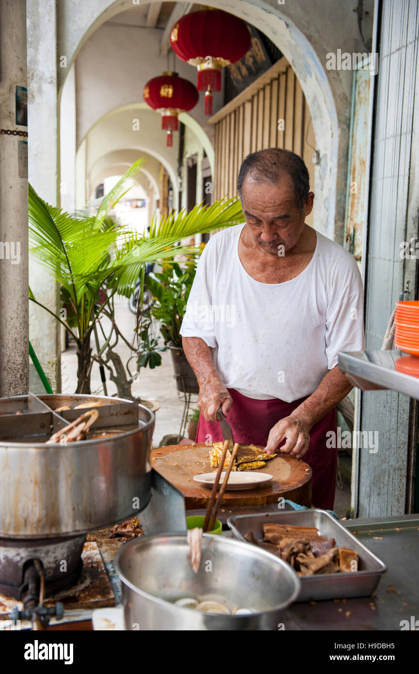 Un uomo anziano prepara i brasati al Tai Buan porridge, un Cinese sulla mensa del Penang Muntri Street che si specializza in congee o porridge cinese Foto Stock