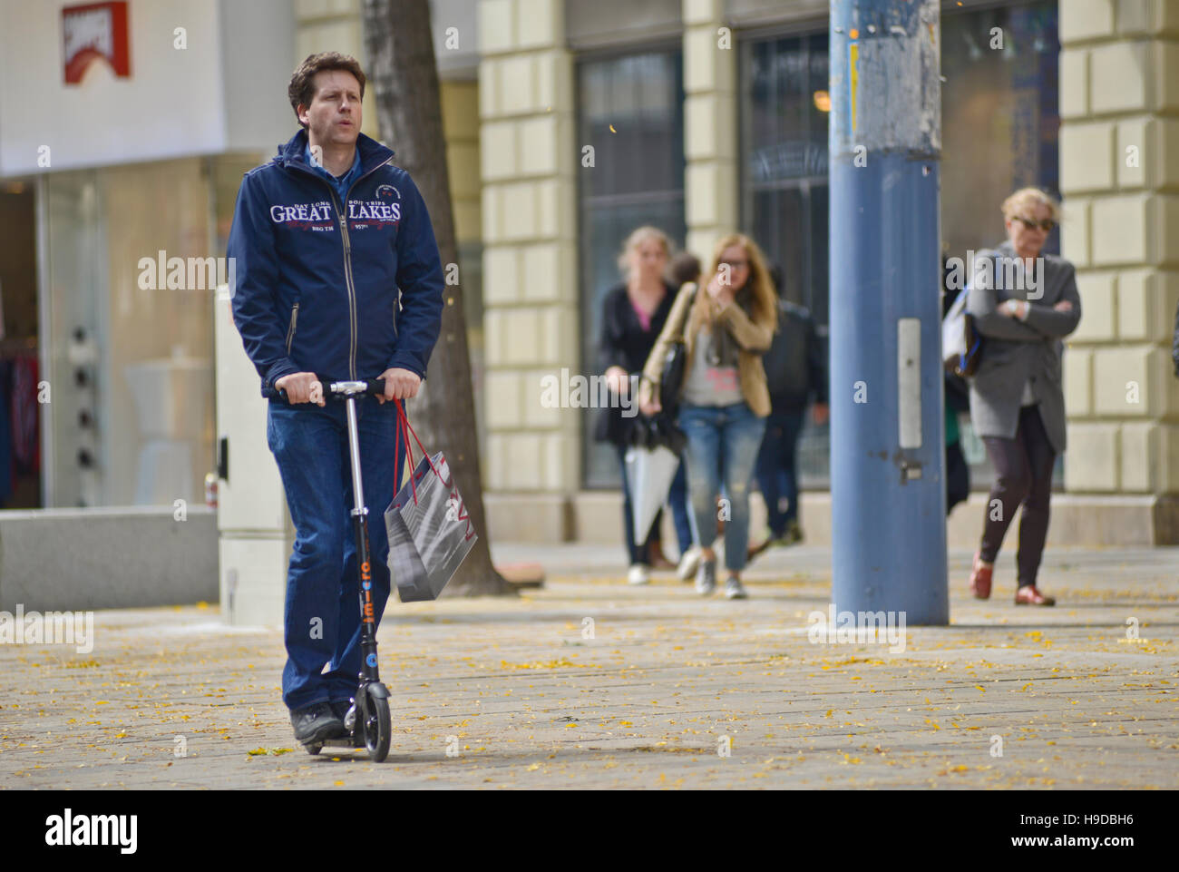 Uomo a cavallo di uno scooter lungo le strade di Vienna, Austria Foto Stock