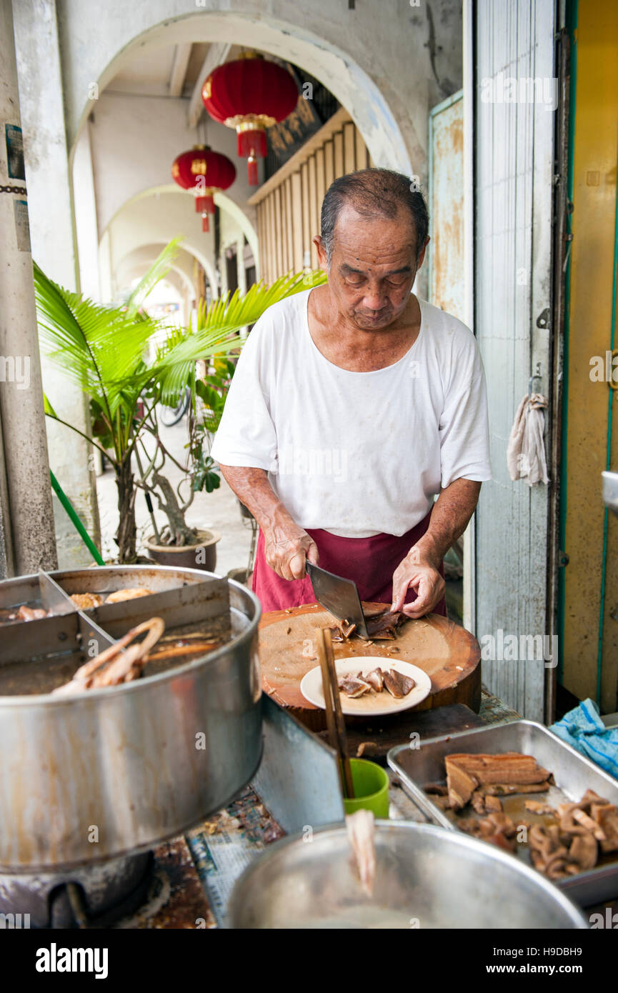 Un uomo anziano prepara i brasati al Tai Buan porridge, un Cinese sulla mensa del Penang Muntri Street che si specializza in congee o porridge cinese Foto Stock