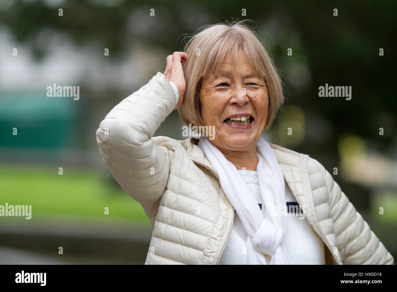 Felice anziani donna giapponese ride e graffi la sua testa Foto Stock