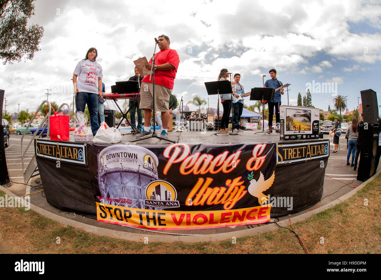 Altoparlanti e animatori di raccogliere su un palco in una dimostrazione contro la pista della violenza in una Santa Ana CA, al parco della città. Nota banner con segno e il logo t shirt. Foto Stock