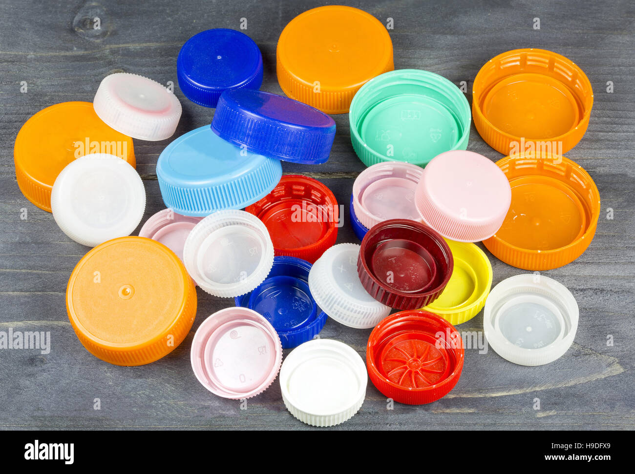 Colorati i tappi in plastica su grigio Sfondo di legno Foto Stock