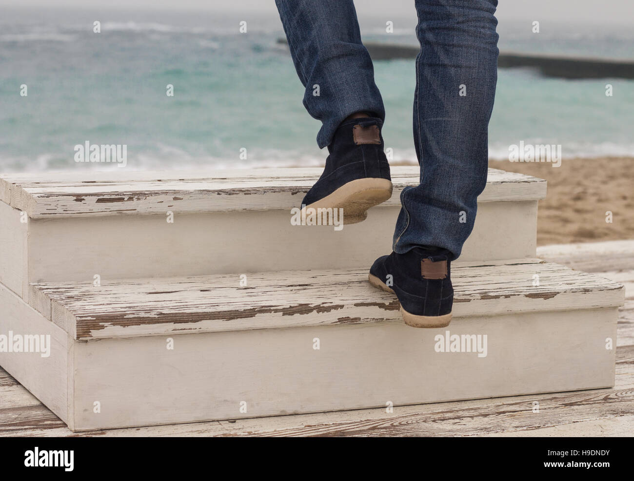 Uomo di passeggiate a piedi fino sulla scaletta di legno. Mare sullo sfondo Foto Stock