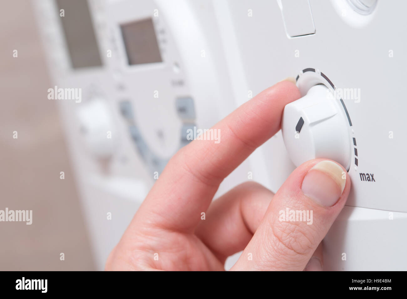 Dita regolare la manopola su una caldaia bianco o apparecchio elettrico. Sembra essere girando verso l'impostazione MAX. Altri pulsanti e un digital disp Foto Stock