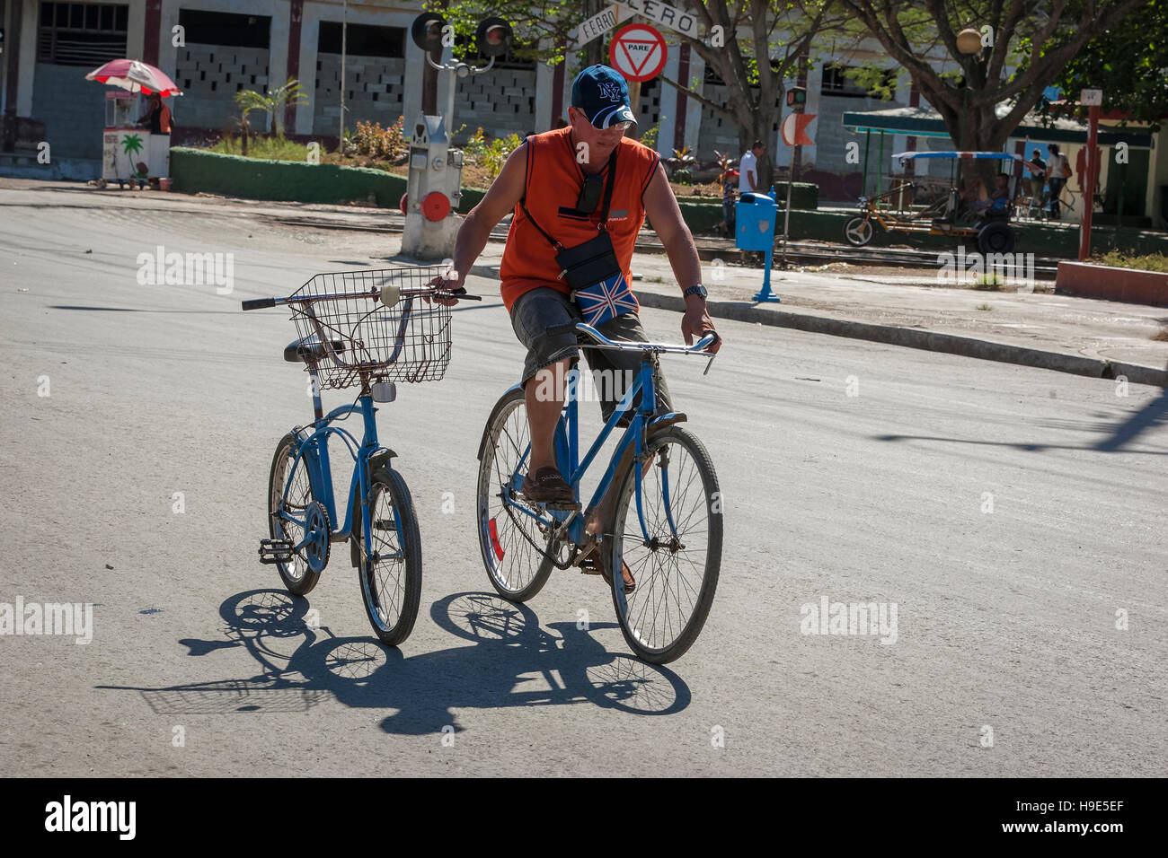 Uomo su una bicicletta in strada nel centro di Cuba con la sua mano che tiene un'altra bicicletta con nessuno su di esso Foto Stock